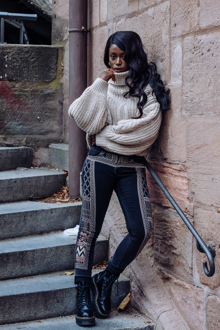 Ama Poku from the blog Phuck it Fashion wearing a chunky knit sweater and embroidered jeans