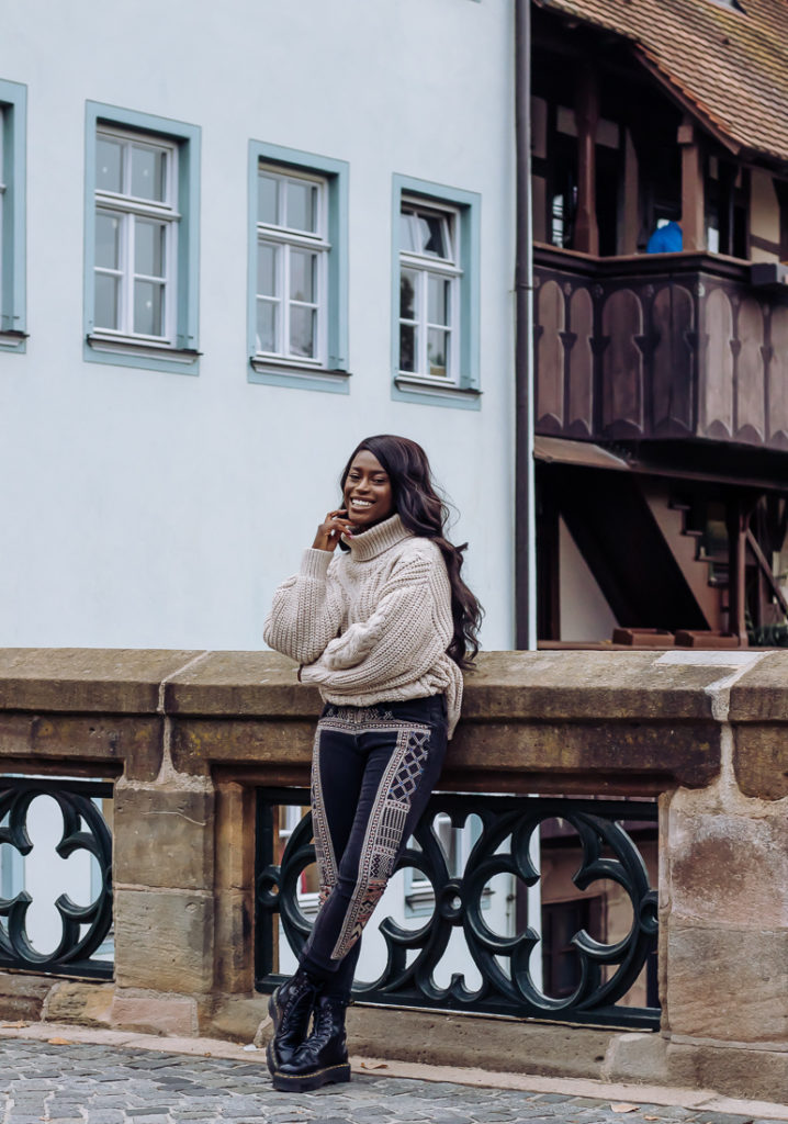 Ama Poku from the blog Phuck it Fashion wearing a chunky knit sweater and embroidered jeans